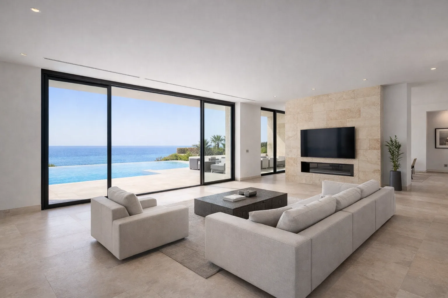 Open-plan living room interior with floor-to-ceiling sliding glass doors connecting directly to the terrace and pool area.