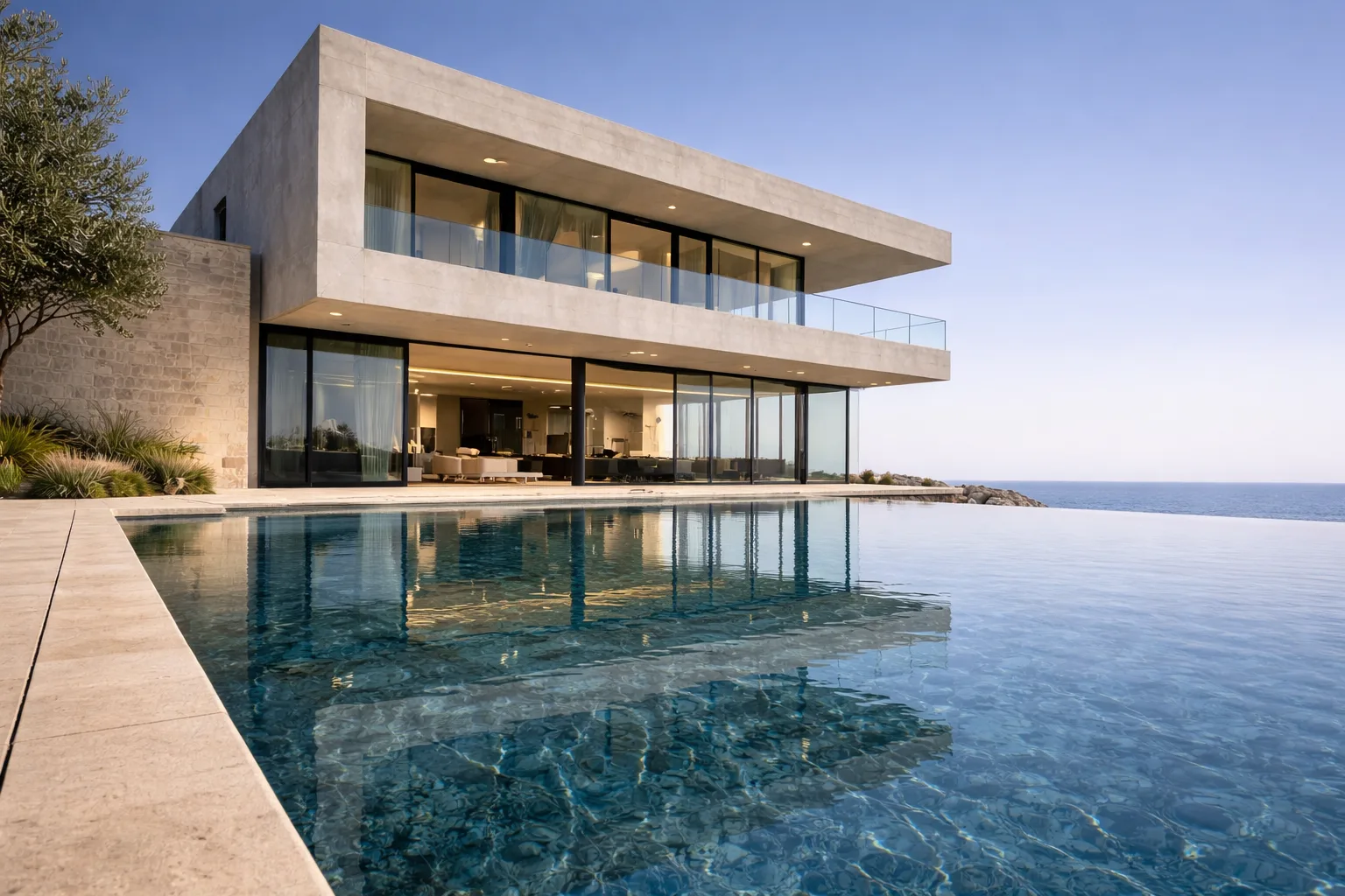 Low pool-level angle emphasizing the cantilevered concrete volume with reflections in the infinity pool